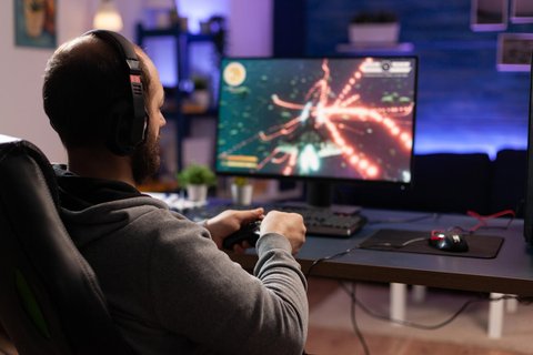 44620948 person playing video games with controller on computer